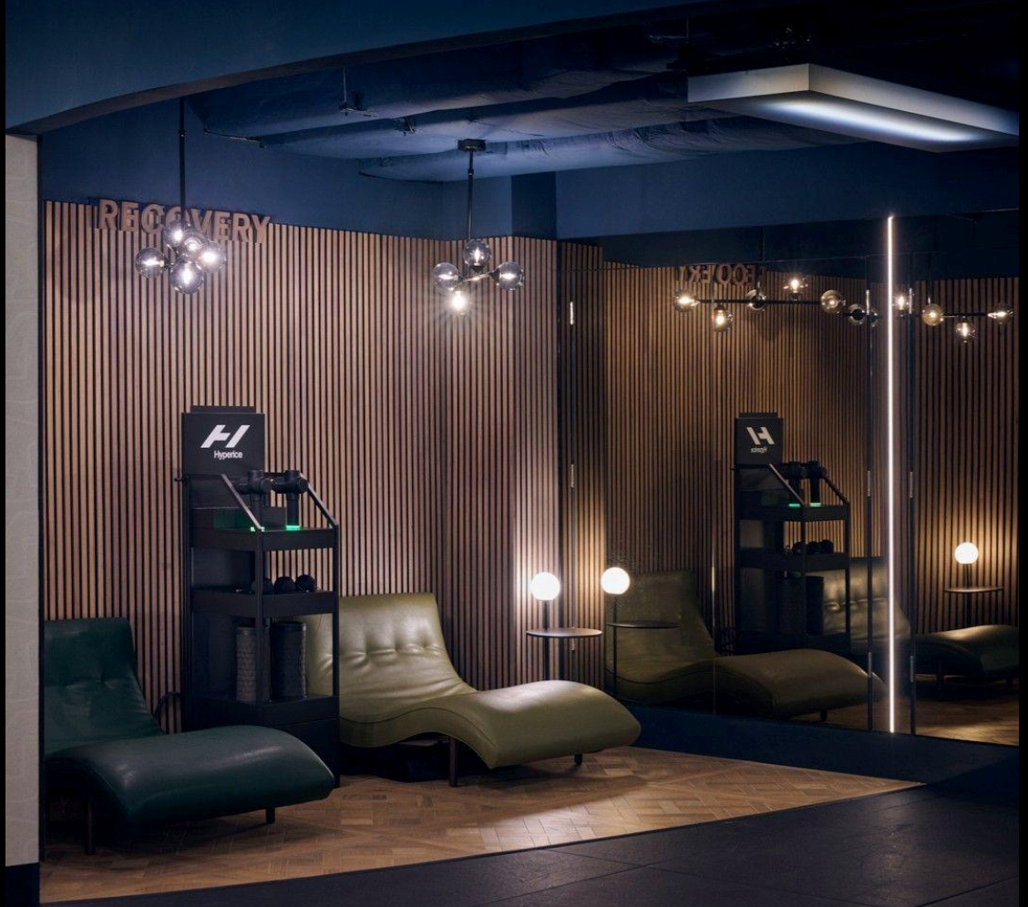 Fitness recovery lounge equipped with compression therapy systems and ergonomic relaxation chairs for muscle recovery.