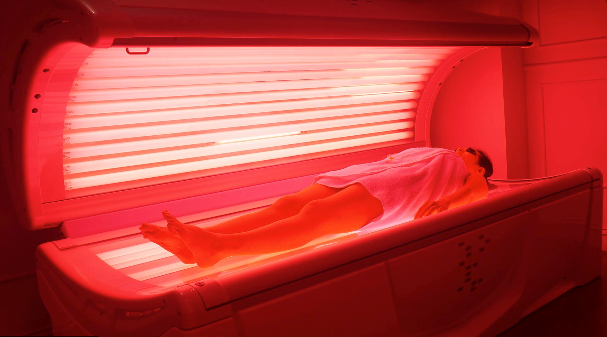 Person relaxing in a full-body LED light therapy bed during a red light wellness and recovery session.