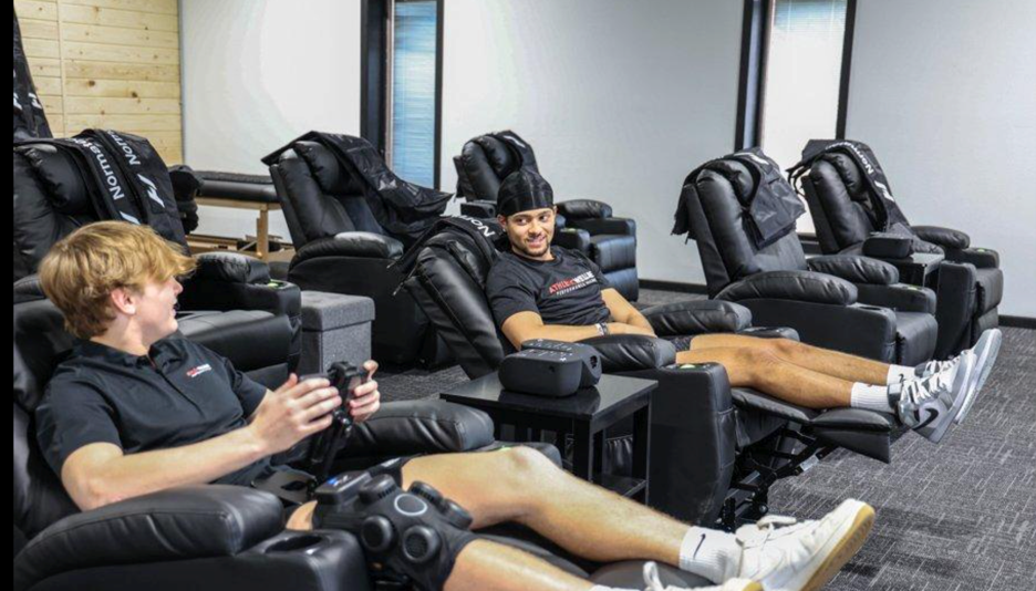 Athletes using recovery chairs for post-workout recovery
